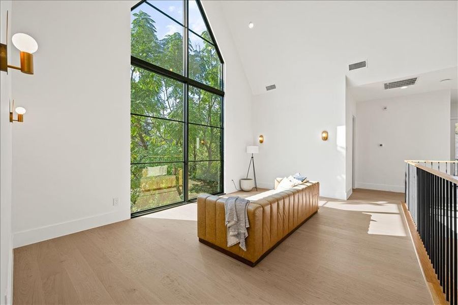 Living room with high vaulted ceiling, light wood-style flooring, and recessed lighting