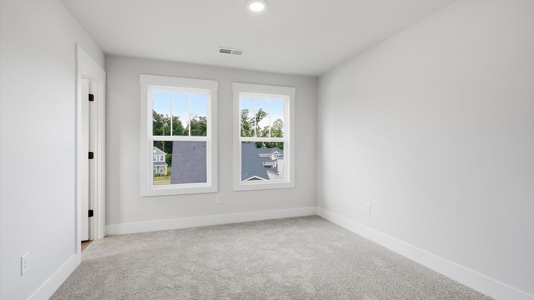 Accomplished design in this restful bedroom featuring plush carpet and oversized window views in Anderson, SC