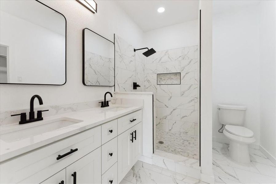 Full bath with marble finish floor, a tile shower, and a sink