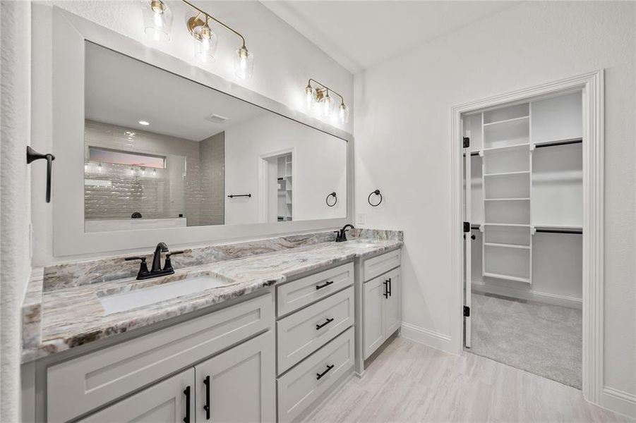 Full bathroom featuring double vanity, a shower, and a spacious closet