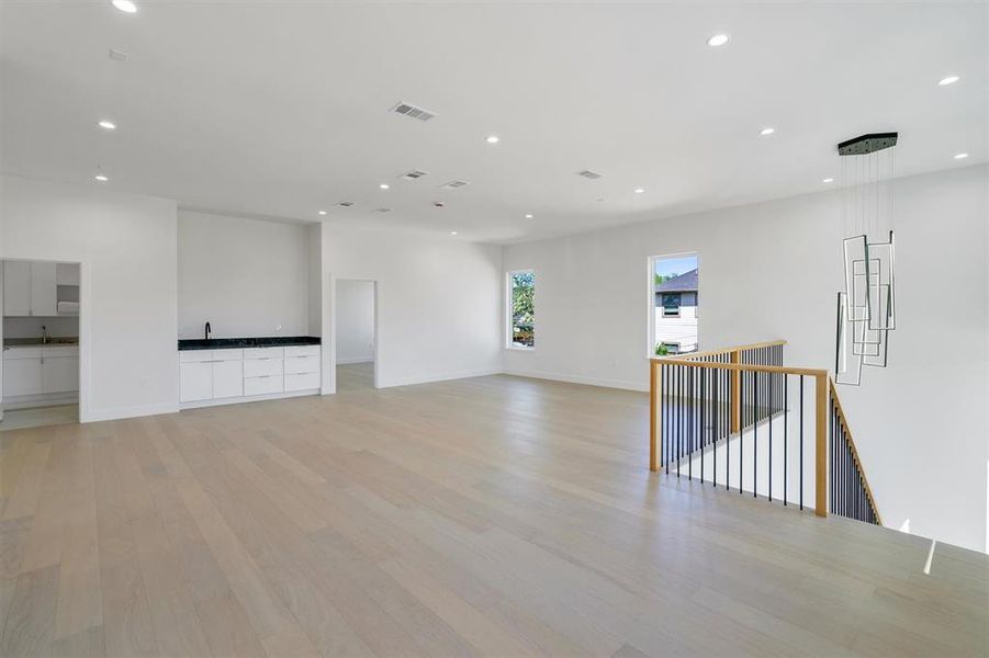 Empty room with light wood-type flooring, baseboards, visible vents, and recessed lighting
