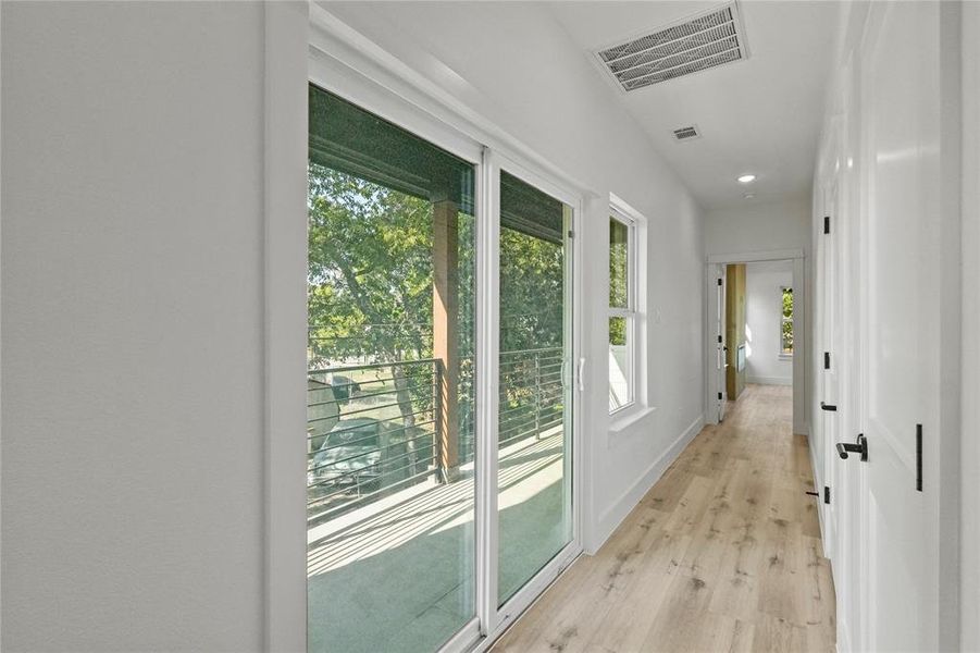 Hall with light hardwood / wood-style floors and a healthy amount of sunlight