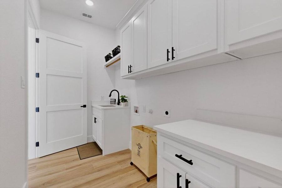 Laundry area featuring hookup for a washing machine, cabinet space, light wood-type flooring, electric dryer hookup, and recessed lighting Laundry area featuring hookup for a washing machine, cabinet space, light wood-type flooring, electric dryer hookup, and recessed lighting