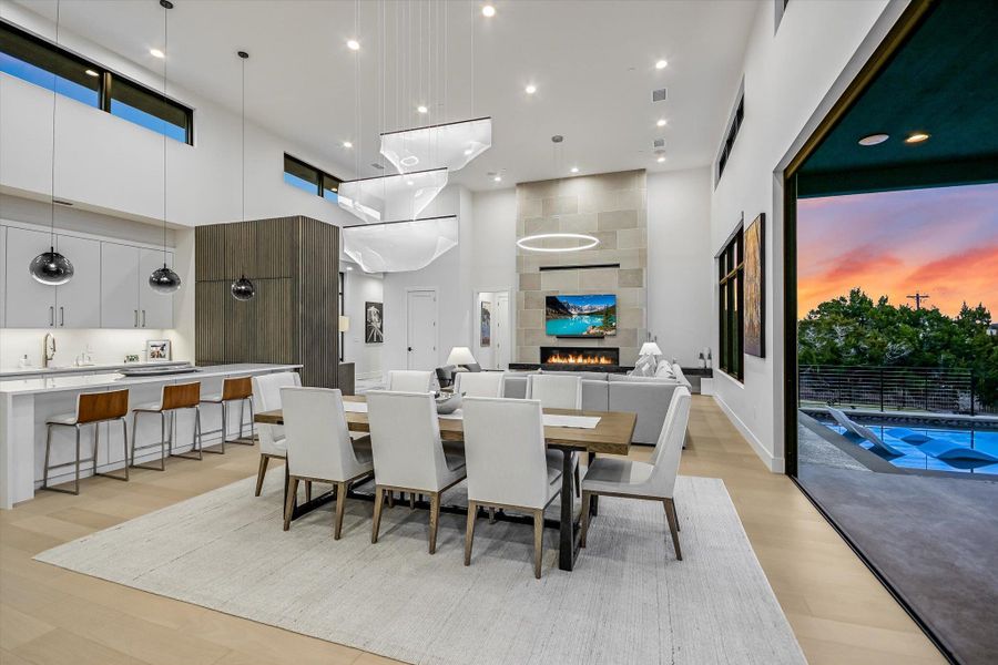 Dining room featuring a high ceiling, a tiled fireplace, recessed lighting, and light wood finished floors Dining room featuring a high ceiling, a tiled fireplace, recessed lighting, and light wood finished floors