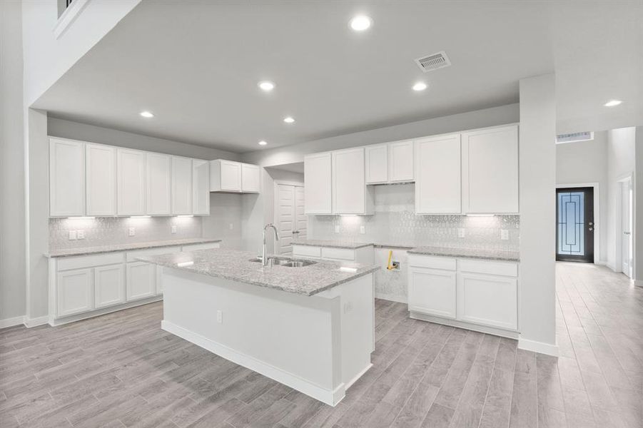 The kitchen is a culinary haven, featuring granite countertops, a tile backsplash, stainless steel appliances, 42” upper cabinets, and undercabinet lighting. Sample photo of completed home with similar floor plan. As-built interior colors and selections may vary.