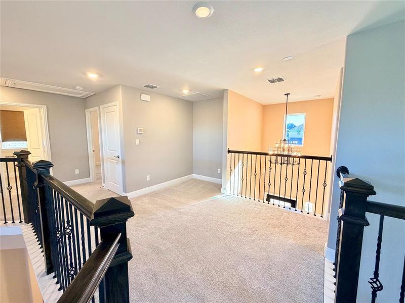 Corridor with a chandelier, light carpet, an upstairs landing, and recessed lighting Corridor with a chandelier, light carpet, an upstairs landing, and recessed lighting