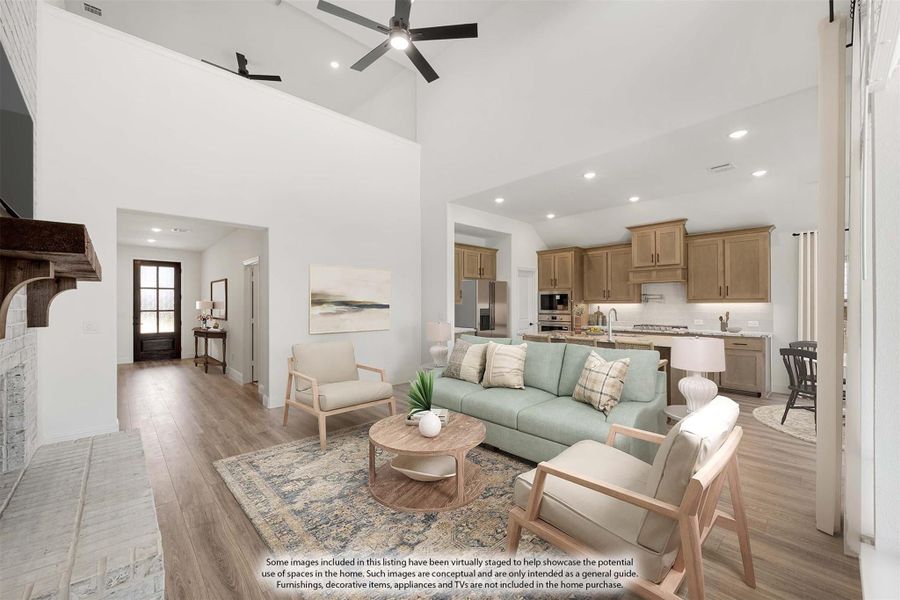 Open-concept living room with high ceilings, ceiling fan, hardwood floors, and kitchen visible in background Open-concept living room with high ceilings, ceiling fan, hardwood floors, and kitchen visible in background