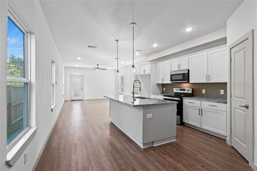 Kitchen with appliances with stainless steel finishes, light stone counters, white cabinets, decorative light fixtures, and recessed lighting