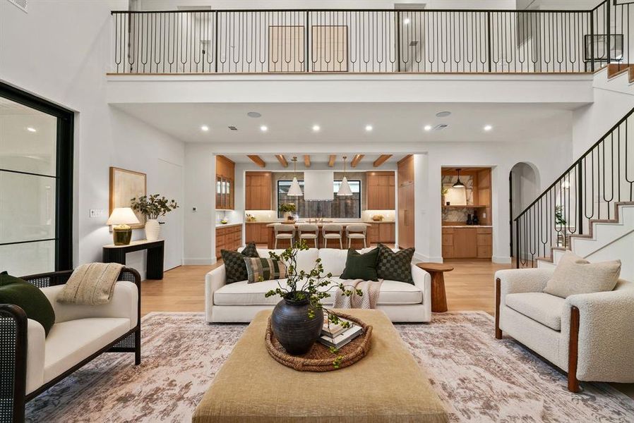 Living room with stairs, recessed lighting, a high ceiling, light wood-style floors, and arched walkways Living room with stairs, recessed lighting, a high ceiling, light wood-style floors, and arched walkways