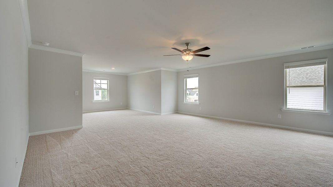 Expansive primary suite with carpet flooring, connected seating room, and ceiling fan light in the Meridian II at Brighton.
