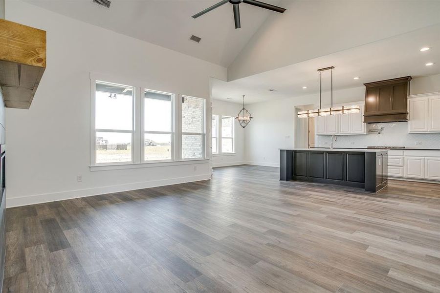 Unfurnished living room featuring ceiling fan, vaulted ceiling, suspended lighting, and dark wood finished floors Unfurnished living room featuring ceiling fan, vaulted ceiling, suspended lighting, and dark wood finished floors