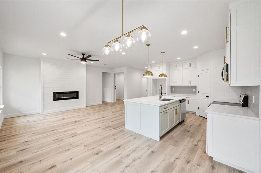 Kitchen featuring light wood finished floors, a fireplace, light countertops, and dishwasher