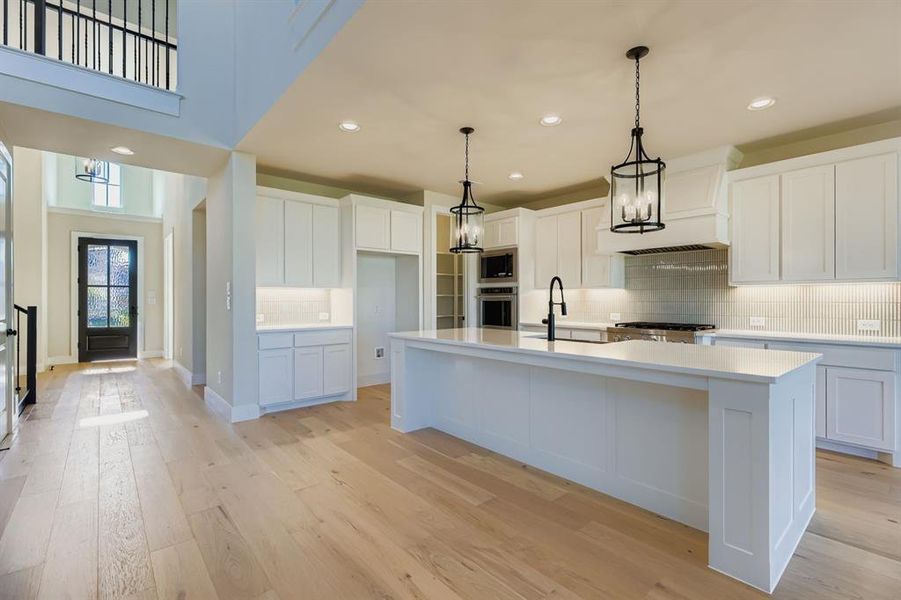 Kitchen with backsplash, white cabinets, pendant lighting, recessed lighting, and light wood-type flooring