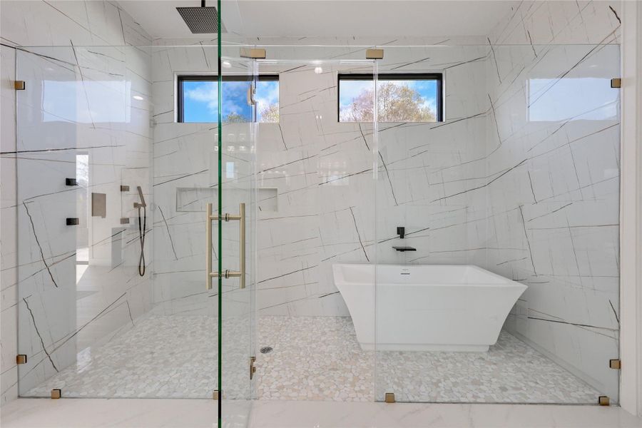 Bathroom with a marble finish shower, tile walls, and a freestanding tub
