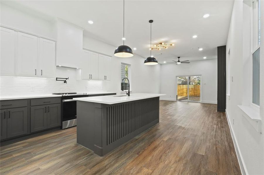 Kitchen with white cabinetry, electric stove, pendant lighting, a kitchen island with sink, and recessed lighting