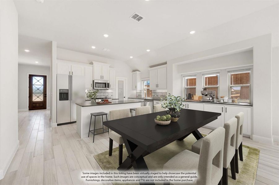 Open dining area with dark wood table and chairs flowing into kitchen with white cabinets and stainless steel appliances Open dining area with dark wood table and chairs flowing into kitchen with white cabinets and stainless steel appliances