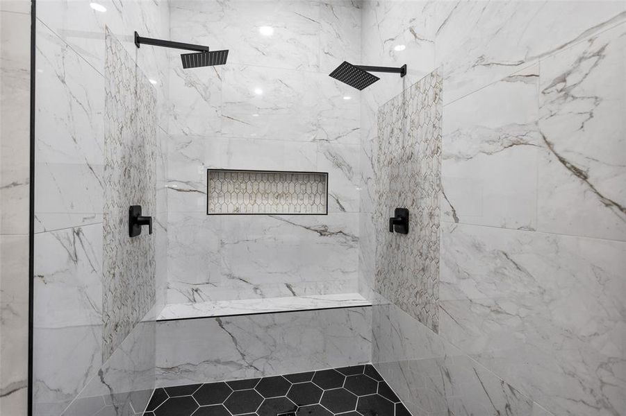 Welcome to your primary shower. Notice the multiple shower heads, bench seating, accessories cove and art tile work.