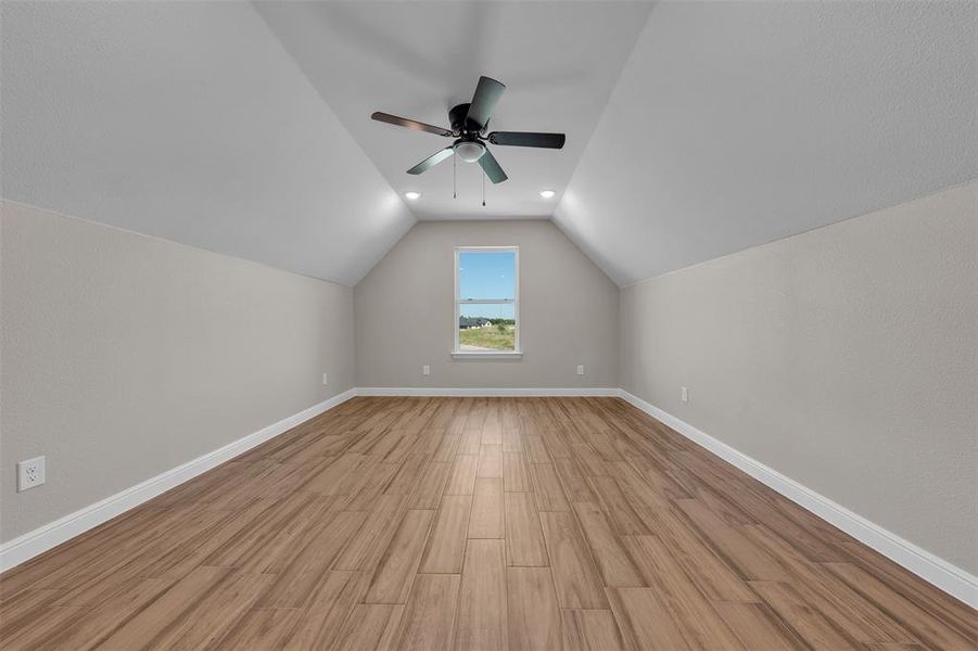Additional living space featuring vaulted ceiling, light wood finished floors, a ceiling fan, and recessed lighting Additional living space featuring vaulted ceiling, light wood finished floors, a ceiling fan, and recessed lighting