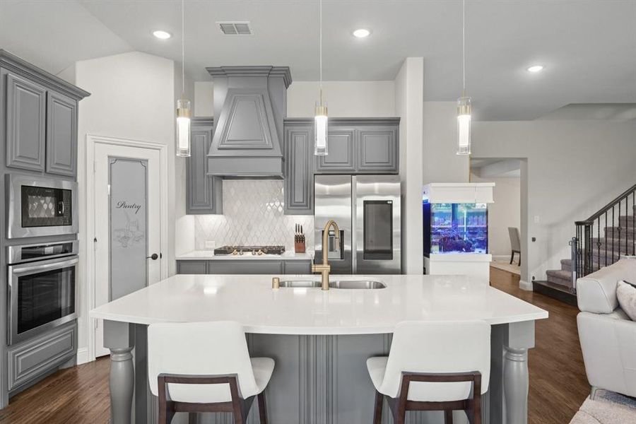 Kitchen with stainless steel appliances, gray cabinetry, custom exhaust hood, open floor plan, and recessed lighting Kitchen with stainless steel appliances, gray cabinetry, custom exhaust hood, open floor plan, and recessed lighting