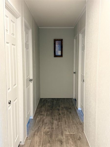 A well-maintained hallway with durable wood flooring leads to several rooms, providing functional access throughout the home. A well-maintained hallway with durable wood flooring leads to several rooms, providing functional access throughout the home.