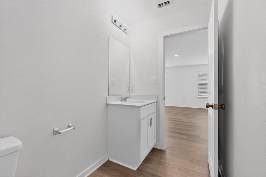 Half bath featuring vanity, light wood finished floors, and a textured wall
