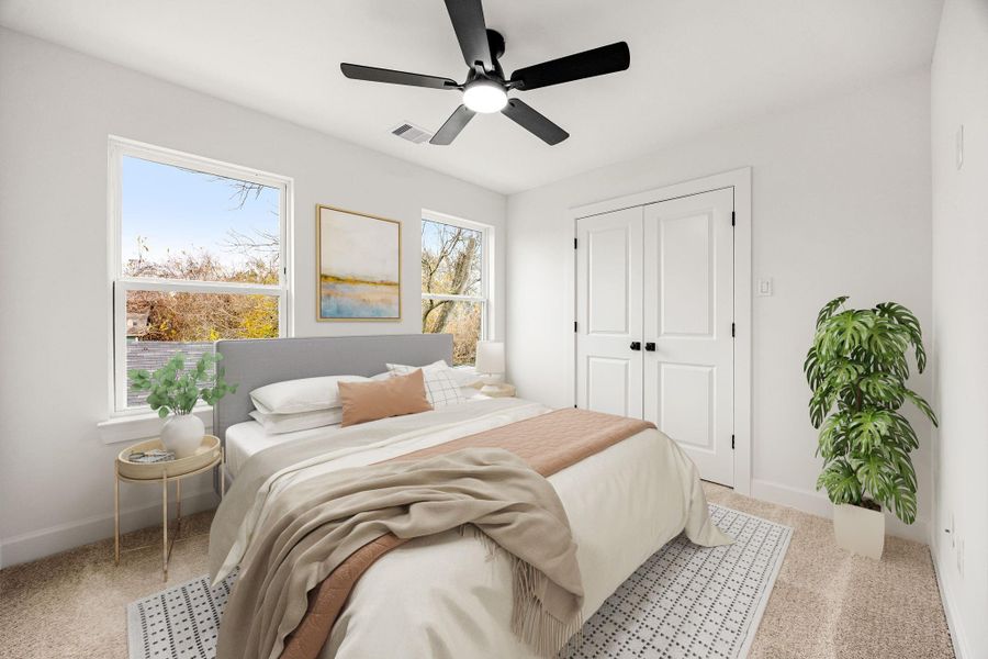 This light-filled bedroom offers a calming retreat with neutral finishes, plush carpeting, ceiling fan, and multiple windows that bring in abundant natural light, creating a comfortable and versatile space ideal for guests or everyday living.