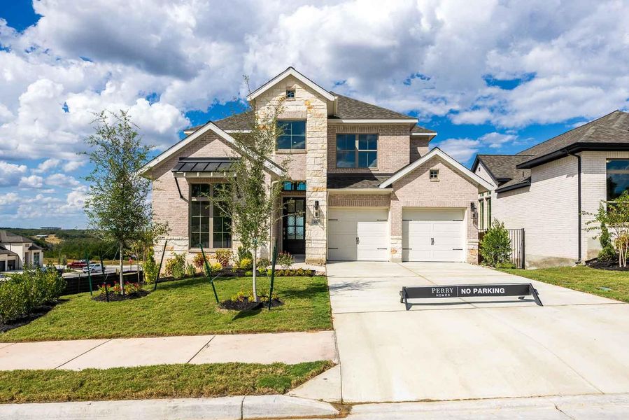 View of front facade featuring stone siding, a front yard, brick siding, and driveway View of front facade featuring stone siding, a front yard, brick siding, and driveway