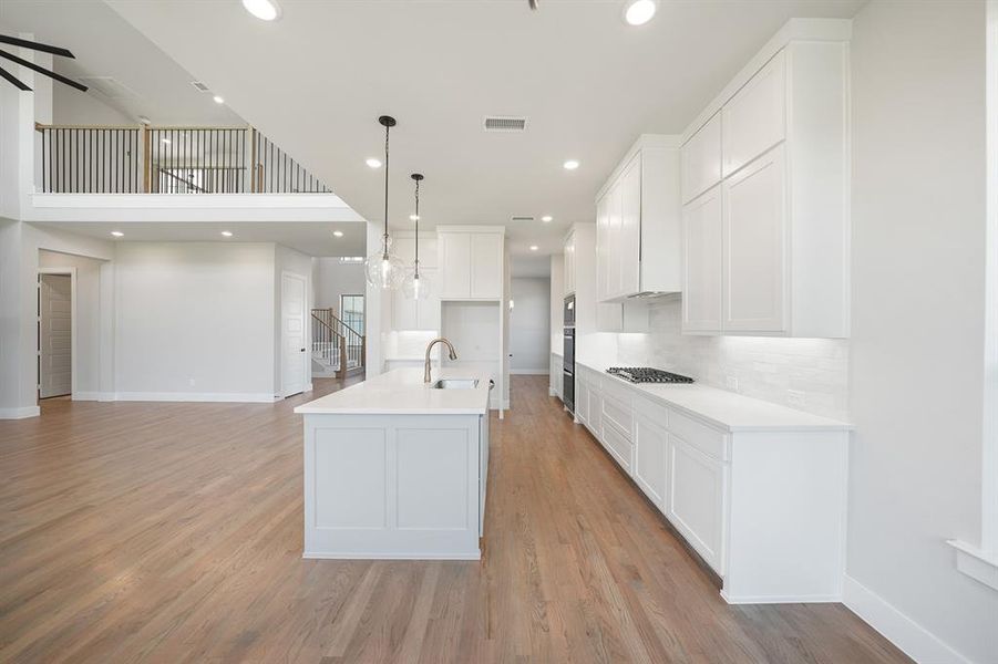 Kitchen with a kitchen island with sink, recessed lighting, white cabinets, hanging light fixtures, and open floor plan Kitchen with a kitchen island with sink, recessed lighting, white cabinets, hanging light fixtures, and open floor plan