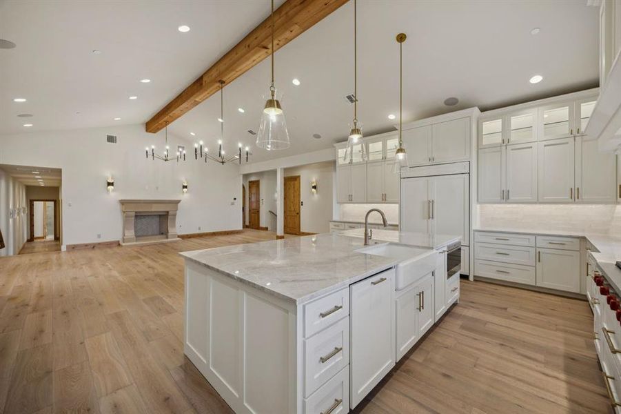 Kitchen featuring glass insert cabinets, decorative backsplash, white cabinetry, light wood-style flooring, and beam ceiling