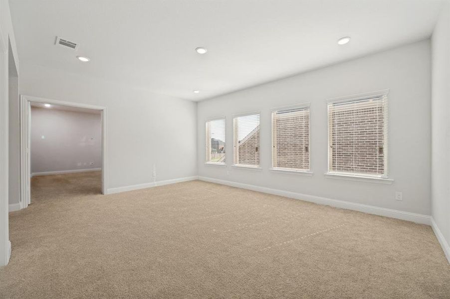Spacious room featuring neutral carpeting, light-colored walls, recessed lighting, and three windows with blinds