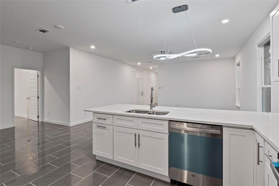 Kitchen with dishwasher, sink, hanging light fixtures, and white cabinets