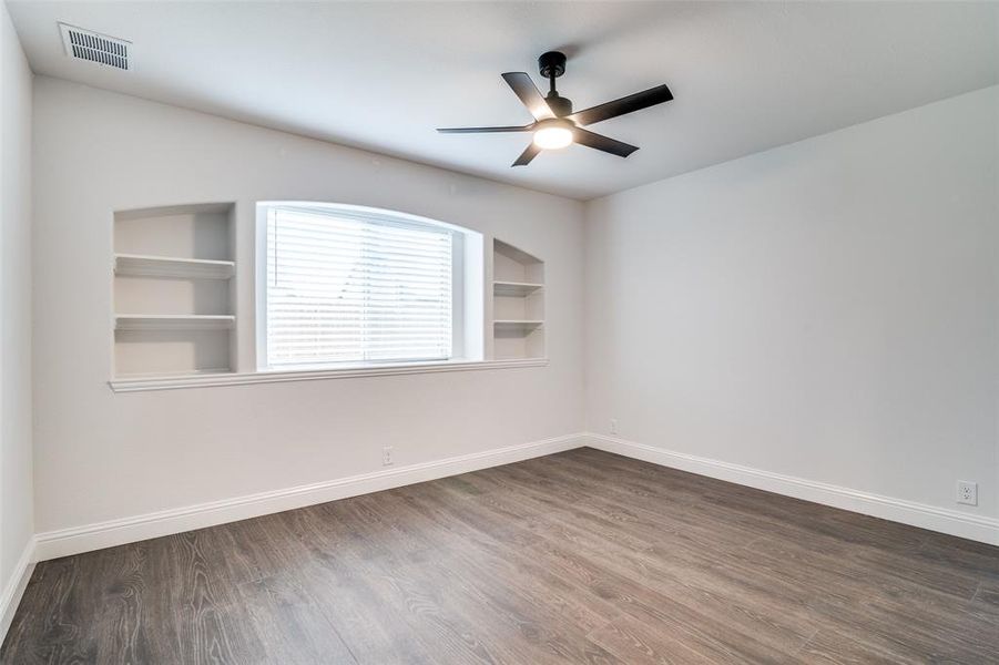 Bedroom featuring built in shelves, ceiling fan, and dark hardwood / wood-style flooring