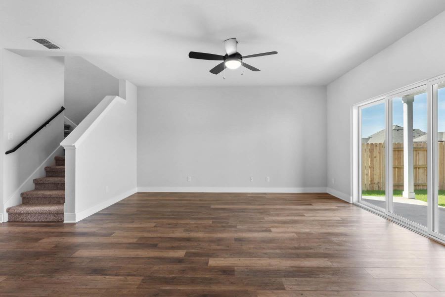 Rich hardwood-style flooring and a modern ceiling fan elevate this open living area. Rich hardwood-style flooring and a modern ceiling fan elevate this open living area.