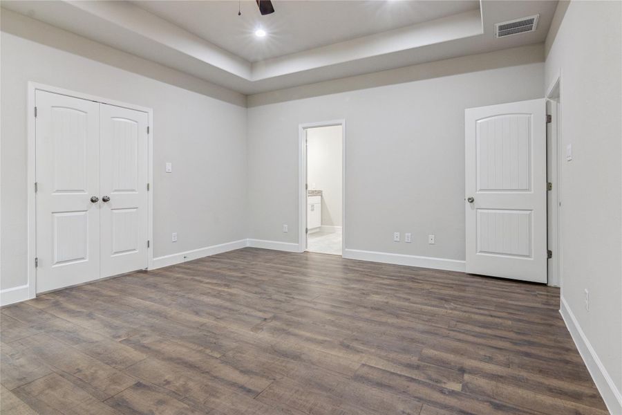 The primary bedroom features a recessed ceiling with modern lighting. It includes double doors walk-in closet, and an en-suite bathroom, creating a versatile, comfortable space.