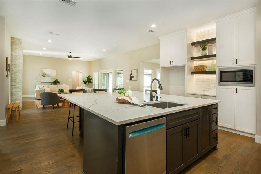 Kitchen with white cabinets, stainless steel appliances, sink, dark hardwood / wood-style floors, and a kitchen island with sink