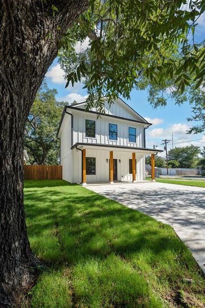 Modern farmhouse with board and batten siding, a porch, and concrete driveway