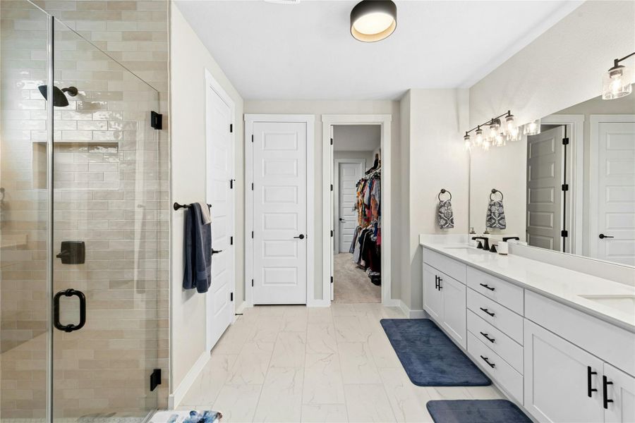 Full bathroom featuring a shower stall, double vanity, and a walk-in closet