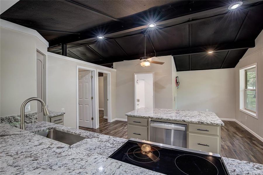 Kitchen featuring sink, lofted ceiling with beams, stainless steel dishwasher, and white cabinets