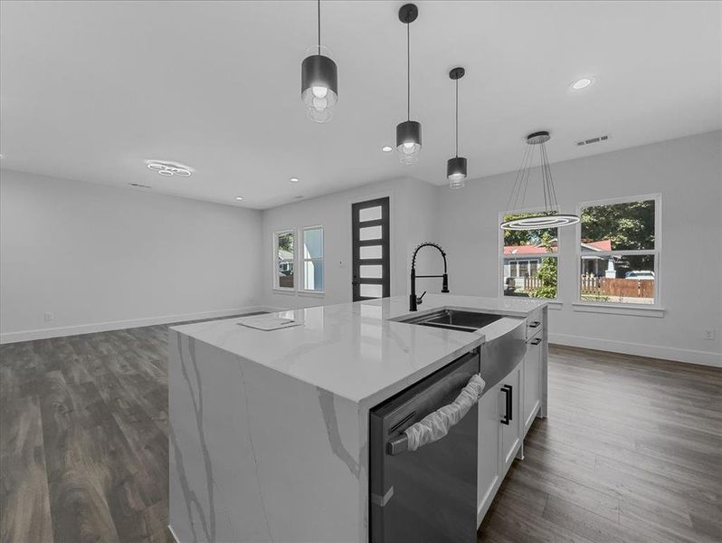 Kitchen with pendant lighting, stainless steel dishwasher, light stone counters, dark wood-type flooring, and recessed lighting Kitchen with pendant lighting, stainless steel dishwasher, light stone counters, dark wood-type flooring, and recessed lighting