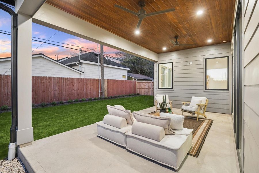 Inviting covered back porch with ceiling fans, overlooking the backyard—a comfortable space to unwind year-round