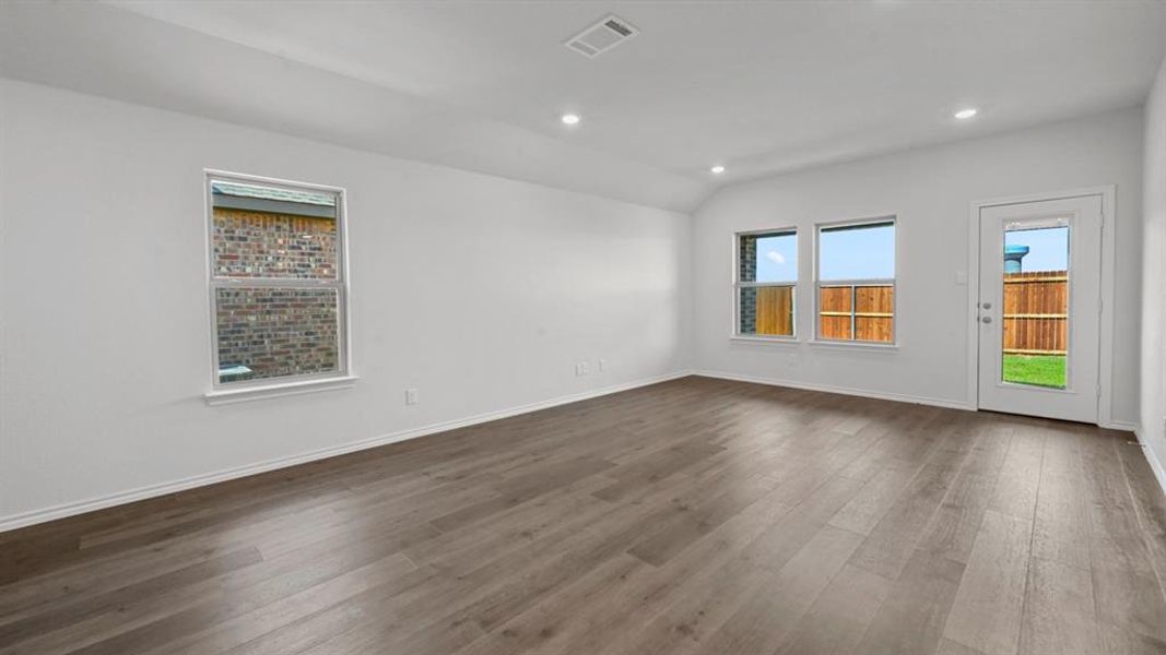 Spacious room featuring wood-finish flooring, recessed lighting, multiple windows, and a glass-paneled exterior door