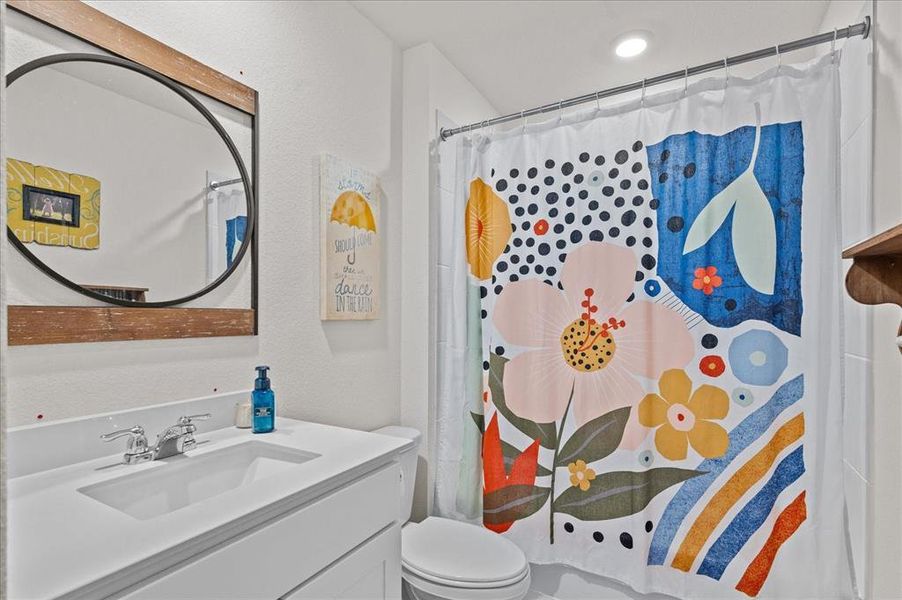 Bathroom featuring vanity, toilet, and curtained shower