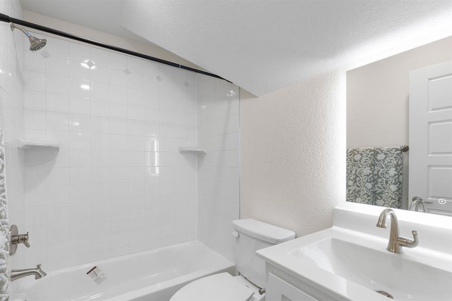 Bathroom with a textured wall, bathtub / shower combination, vanity, and a textured ceiling Bathroom with a textured wall, bathtub / shower combination, vanity, and a textured ceiling