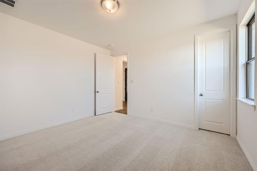 Empty room with a healthy amount of sunlight and light colored carpet