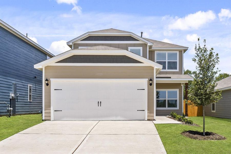 View of front of property featuring a front lawn and a garage