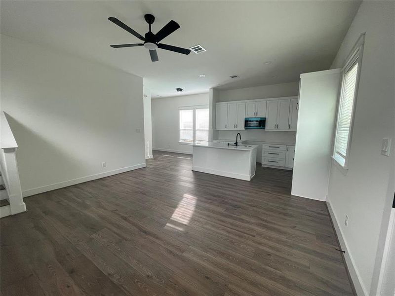 Unfurnished living room featuring ceiling fan and dark wood finished floors