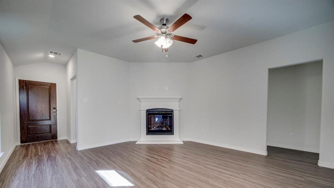 Unfurnished living room featuring lofted ceiling, ceiling fan, a glass covered fireplace, and dark wood-style flooring