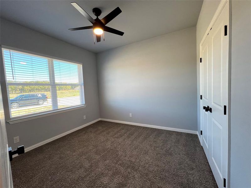 Empty room with ceiling fan and dark carpet