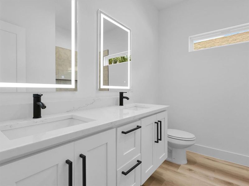 Bathroom featuring toilet, hardwood / wood-style flooring, and dual bowl vanity