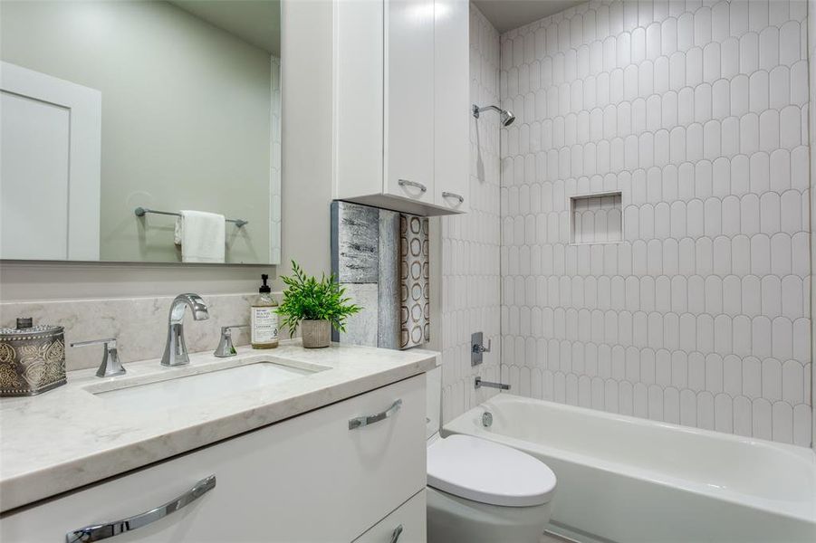 Full bathroom featuring tiled shower / bath combo, toilet, and vanity